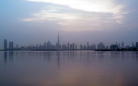 Panoramic view of the Dubai skyline with Burj khalifa and other sky scrapers forming silhouette captured after the sunset time at the Dubai creek, ras al khor, UAE.