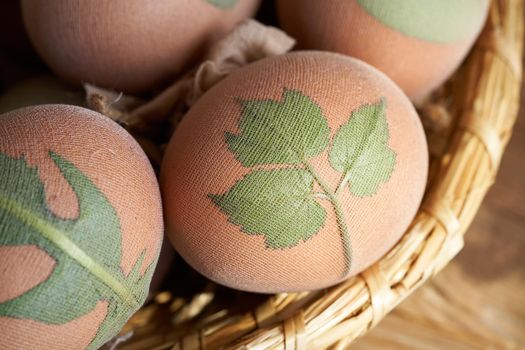 Raw Easter eggs with fresh plant leaves attached to them with stockings, ready to be dyed with onion peels