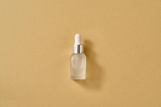 A bottle of essential oil on beige background with copy space