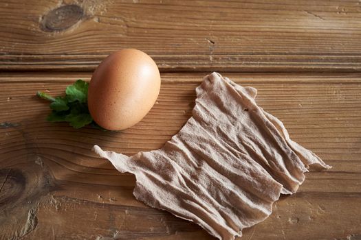 Raw Easter egg with a green leaf and a piece of old nylon stockings - preparation for dyeing with onion peels