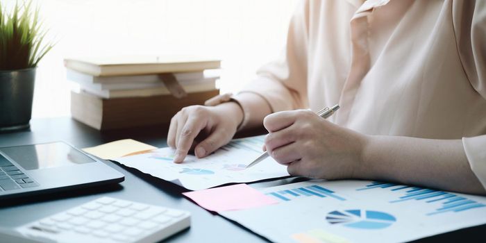 woman checking paperwork from accounting department to analyse number on document, using laptop check business database, information comparing. Typing keyboard for recording.