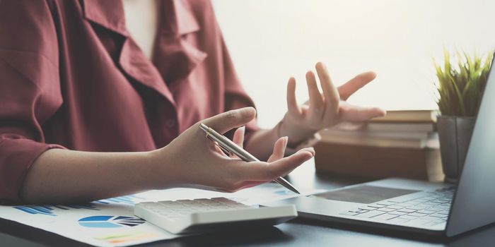 woman checking paperwork from accounting department to analyse number on document, using laptop check business database, information comparing. Typing keyboard for recording.