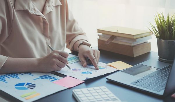 woman checking paperwork from accounting department to analyse number on document, using laptop check business database, information comparing. Typing keyboard for recording.