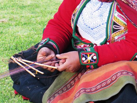 Close up of Peruvian lady in authentic dress spinning yarn by hand. (Peru)