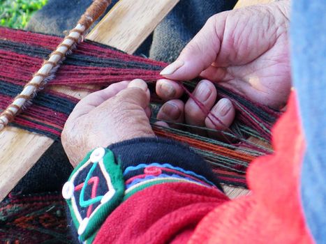 Close up of Peruvian lady in authentic dress spinning yarn by hand. (Peru)