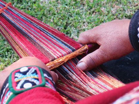 Close up of Peruvian lady in authentic dress spinning yarn by hand. (Peru)