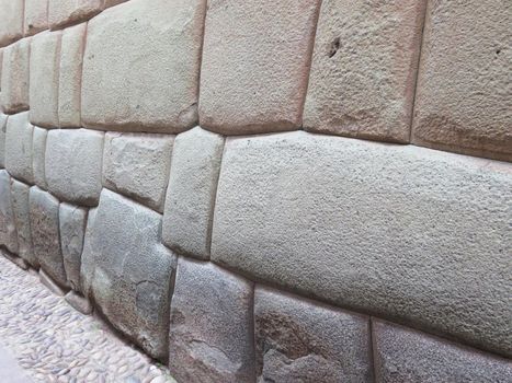 Inca wall made of natural volcanic stones, perfectly shaped, heritage of Inca history and architecture in Cusco, Peru.