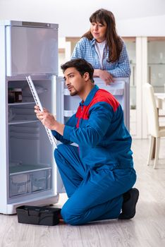 Man repairing fridge with customer