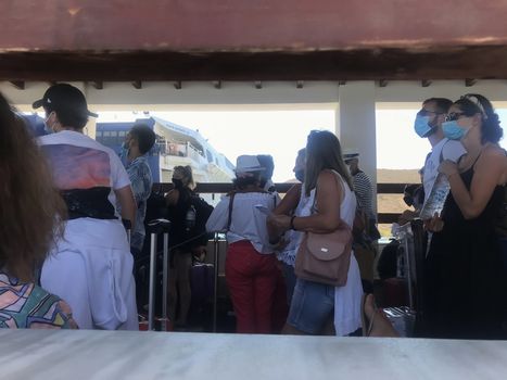 People with face protection prior to departure in the port of the Cycladic island.