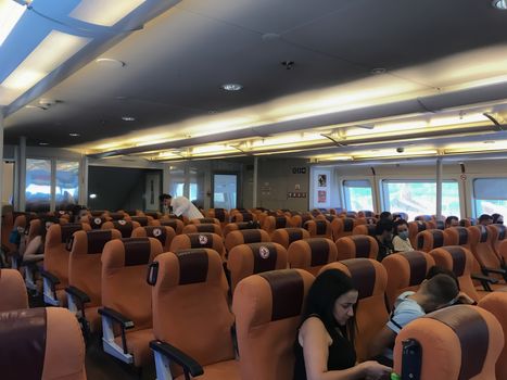 People with face protection at boat with keep empty seats distance designation embarking from a Hellenic seaport.