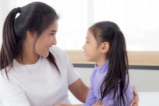 Young asian mom and daughter smiling and eye contact together with care in room, face of mother and girl looking eye with relationship and bonding, emotion and expression, family and love concept.