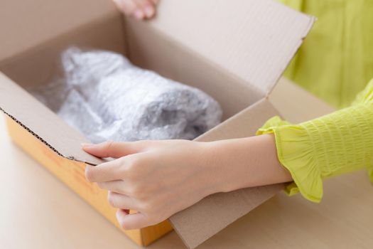 Closeup hand of woman opening parcel box with check product at home, female unpack with knife, delivery and shipping, shipment and express for shop, online shopping store and service concept.