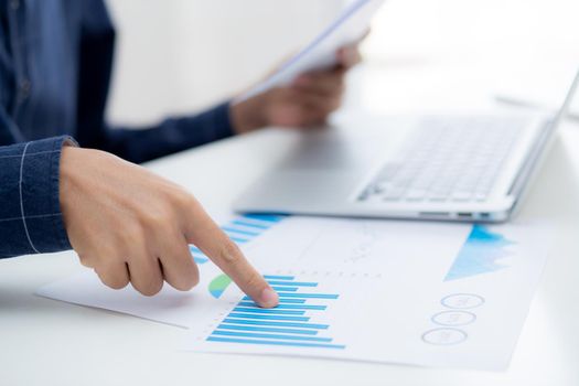 Hand of young business man pointing document data graph and chart paper, marketing and investment, report of statistics profit for financial, economic and growth of finance, management and planning.