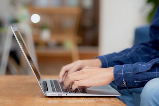 Closeup hand of businessman typing keyboard on laptop computer on desk at home, business man working to internet online, freelance male using notebook on table, communication and lifestyle concept.