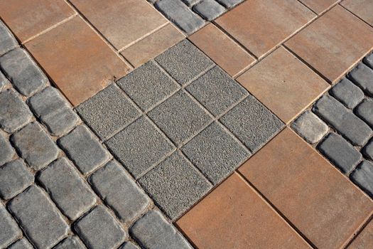 Texture of gray and brown paving slabs on the street, perspective view. Cement brick square stone floor background. Concrete paving slab made of flagstone. The pattern of the sidewalk pavement.