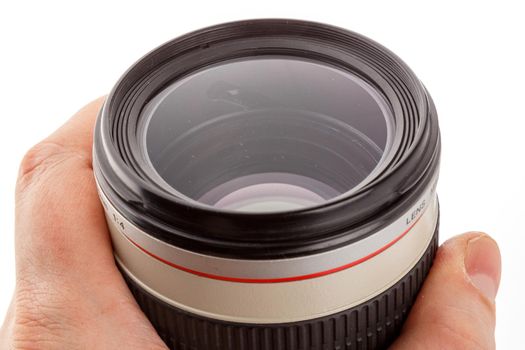 hand holding old white telephoto lens with dust on the surface of its front element.