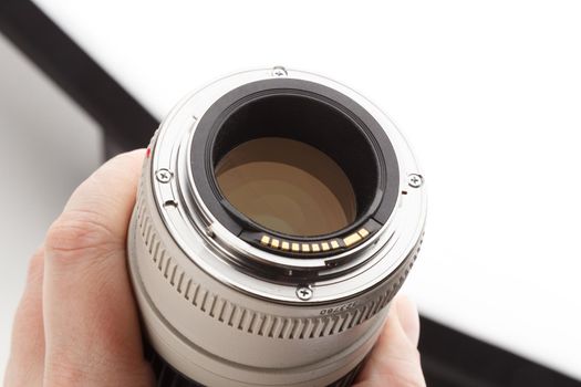 hand holding old white telephoto lens with visible bayonet and rear element.