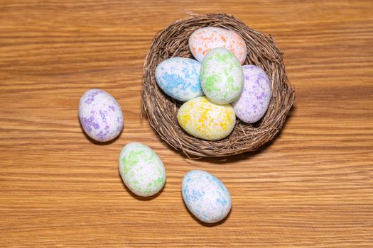 easter colorful eggs in a nest close up on a wooden background. High quality photo