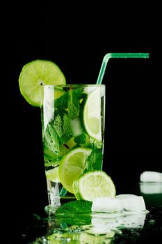 Mojito cocktail with lime, mint and ice on black background