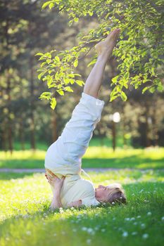 Beautiful mature woman practice yoga in summer park