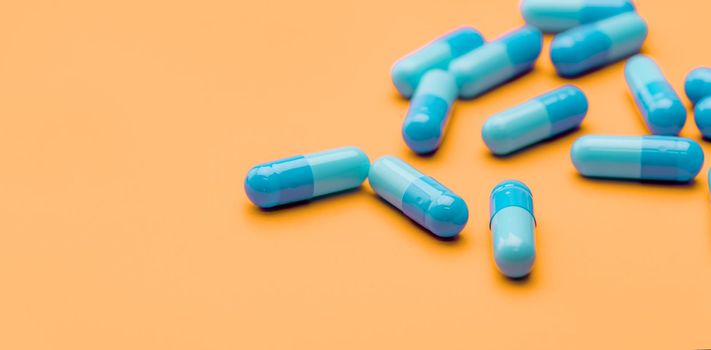 Blue antibiotic capsule pills spread on yellow background. Antibiotic drug resistance. Pharmaceutical industry. Healthcare and medicine concept. Health budget concept. Capsule manufacturing industry.