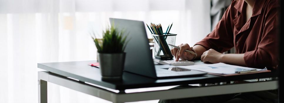 Business woman using calculator for do math finance on wooden desk in office, tax, accounting, statistics home accounring concept