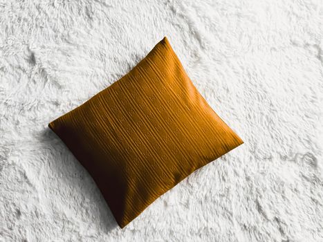 Golden cushion throw pillow on white fluffy plaid blanket as flat lay background, bedroom top view and home decor flatlay