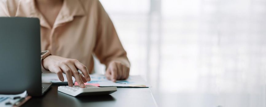 Business woman using calculator for do math finance on wooden desk in office, tax, accounting, statistics home accounring concept