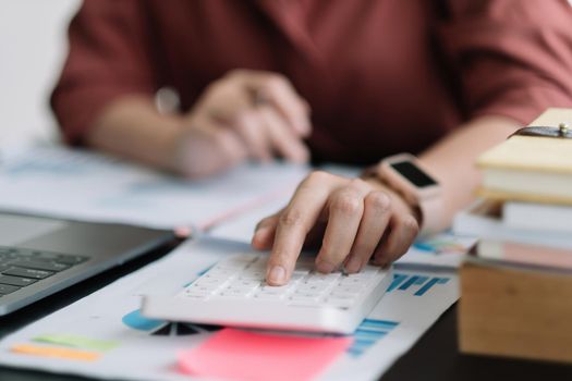 Business woman using calculator for do math finance on wooden desk in office, tax, accounting, statistics home accounring concept