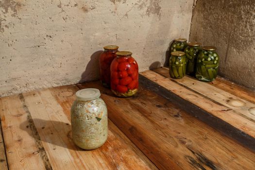 basement with few pickled vegetables in glass jars on wooden planks shelf