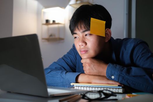 Exhausted tired workaholic young man with sticky note.