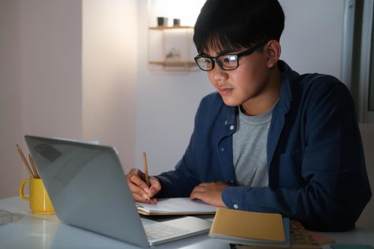 Young collage man learning online at night at his home. 