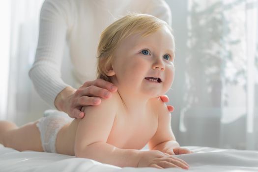 Mom gives her baby a shoulder and back massage. Close-up. A satisfied baby lies on the massage table.