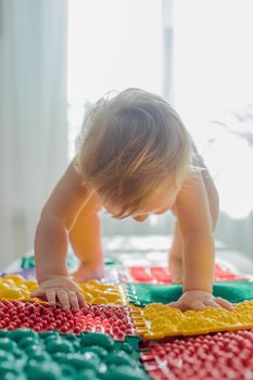 The kid walks barefoot on multi-colored massage rugs. Foot massage