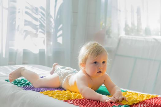 The baby lies on the massage mats with his stomach down. Close-up.