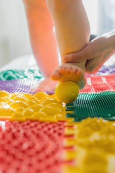 Mom gives the baby a foot massage with massage balls. Close-up