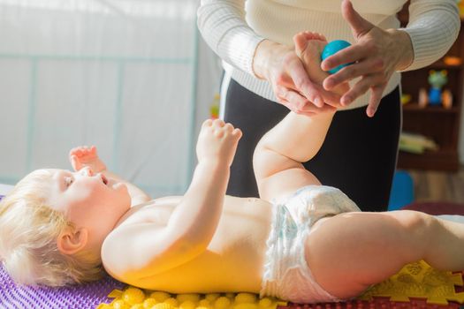 Mom gives the baby a foot massage with massage balls. Close-up