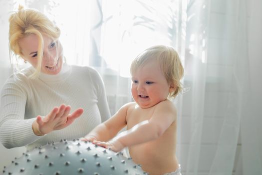 Mom is engaged in gymnastics with the baby on an inflatable ball. Fitball, gymnastics for a child.