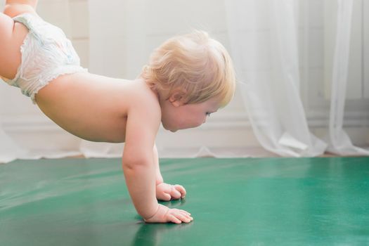 Mom holds the baby by the legs, the baby walks on the rug in her arms. Gymnastics for a child