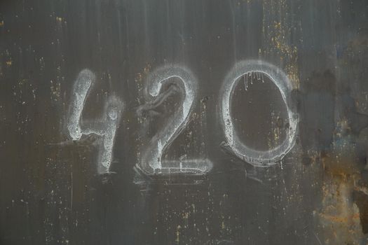 number 420 handwritten on shabby dark gray painted slat sheet steel garage door.