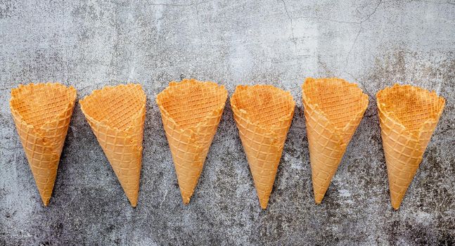 Flat lay ice cream cones collection on dark stone background . Blank crispy ice cream cone with copy space for sweets menu design.