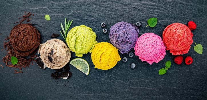 Various of ice cream flavor ball blueberry ,lime ,pistachio ,almond ,orange ,chocolate and vanilla set up on dark stone background . Summer and Sweet menu concept.