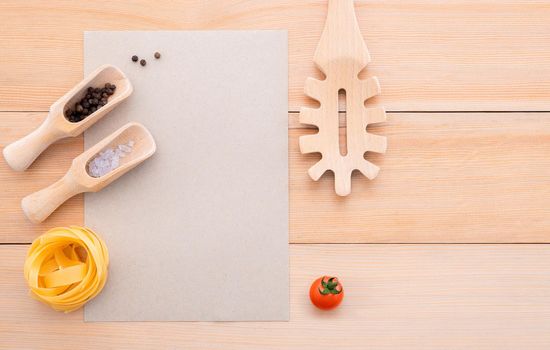 Food background for tasty Italian dishes with blank brown paper and vintage pasta ladle on wooden background. Top view italian foods concept and menu design with copy space.