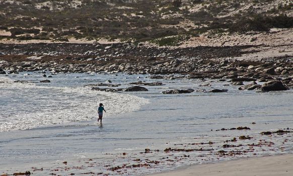 A candid shot of a little girl running in the surf at Hondeklip Bay. South Africa