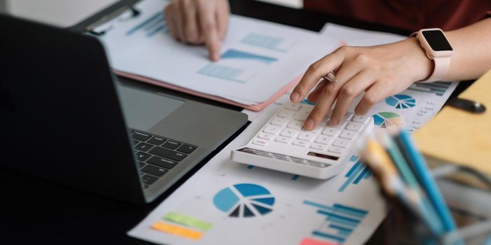 accountant working on desk using calculator for calculate finance report in office.