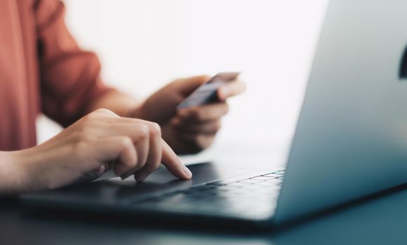 Hands holding plastic credit card and using laptop. Online shopping concept. soft focus.