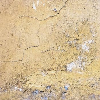 Wall old textured background. Grunge plaster wall with yellow scratched background. Old wall with peel swamp color stucco texture. Rough abstract surface. Vintage wallpaper. Decay and cracks.