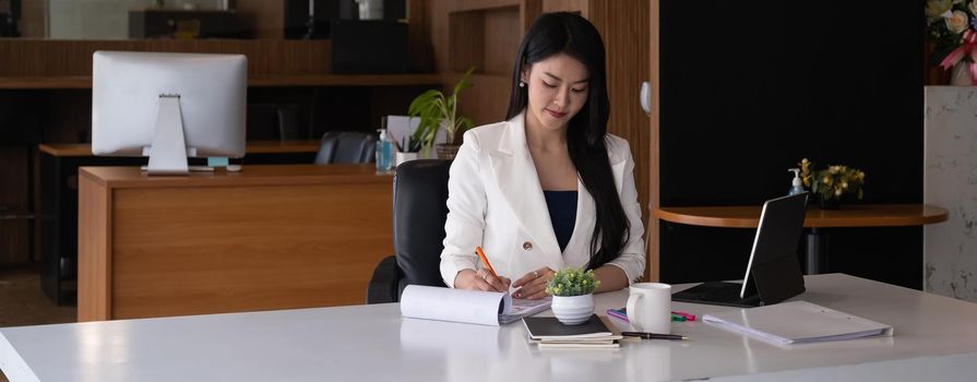 Business woman reading minute of meeting on her notebook in office