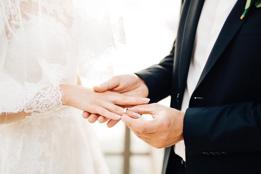 the groom puts the ring on the bride's finger during the wedding ceremony. High quality photo