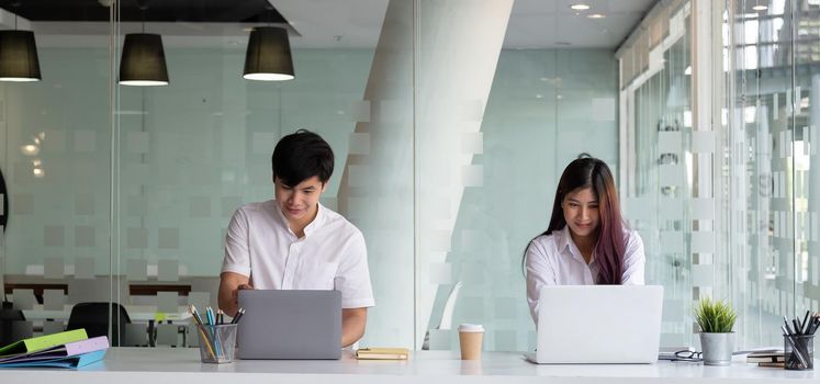 Two business people working with laptop computer at modern office.